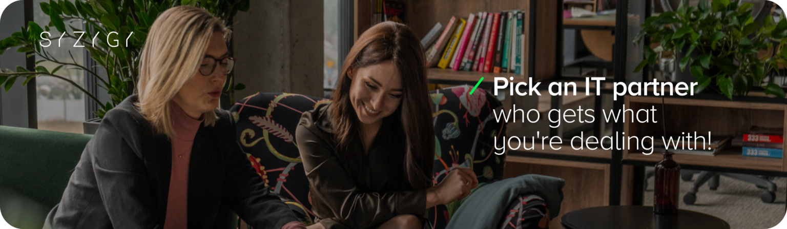 Two people in the office discussing business goals, with the text 'Get an IT partner who understands your challenges,' emphasizing the need for collaboration and support in technology procurement.